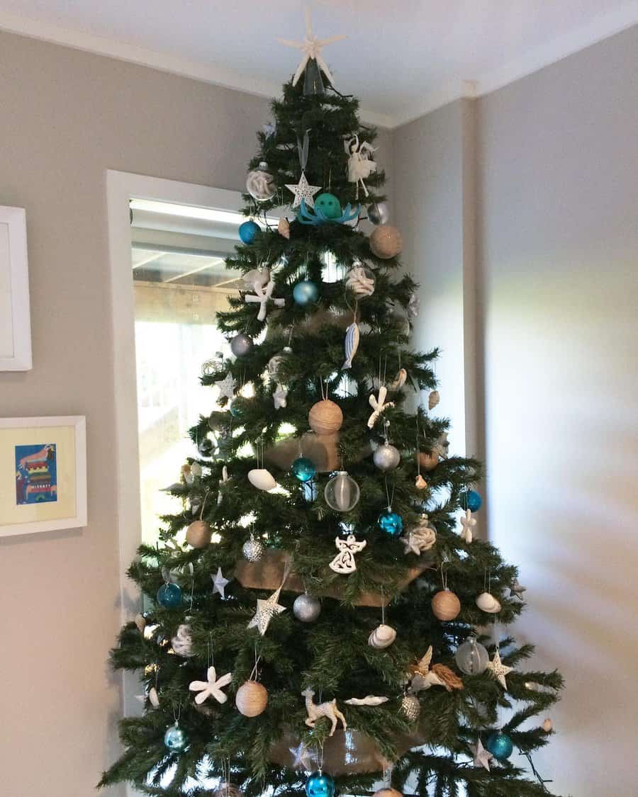 Decorated Christmas tree with blue, white, and silver ornaments in a cozy room