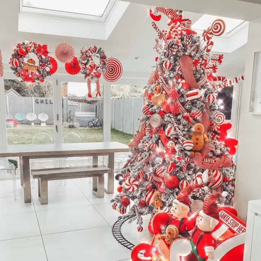 A festive Christmas tree with red and white decorations in a modern dining room