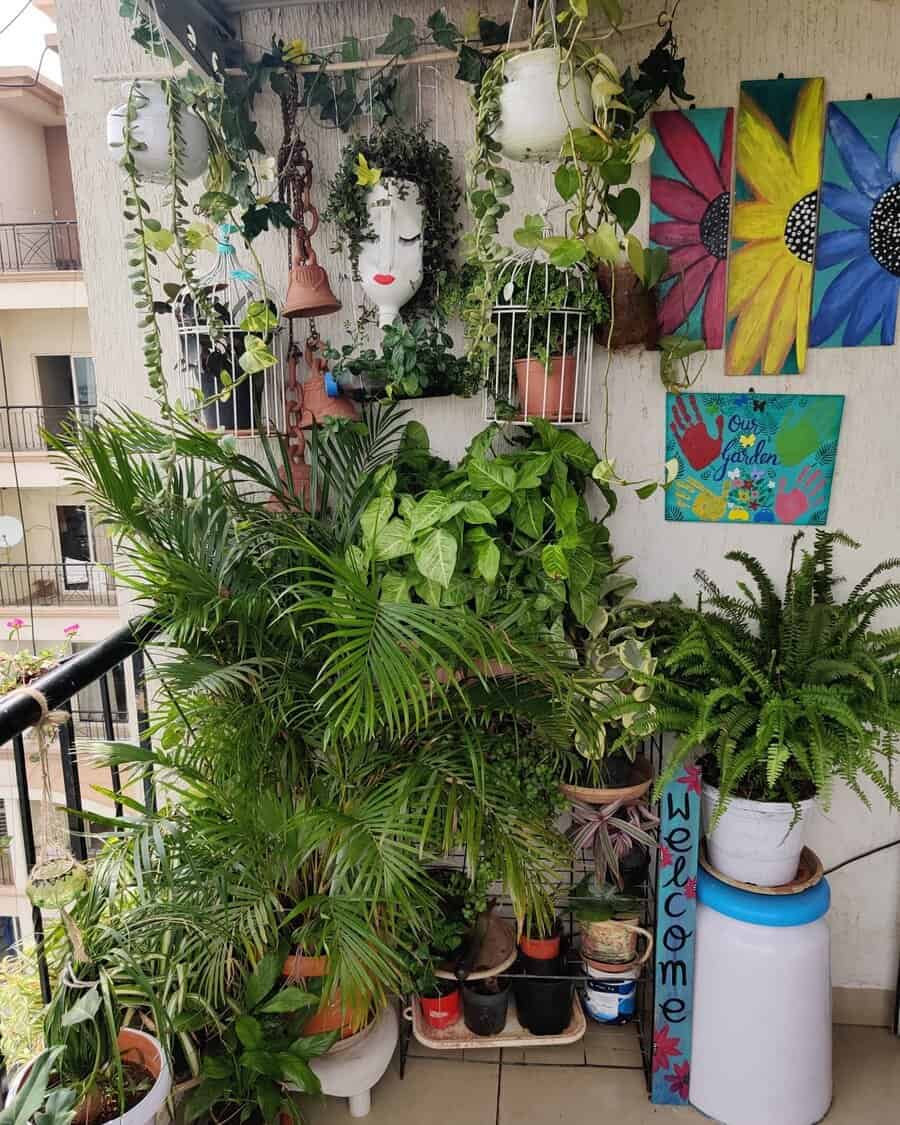 A vibrant balcony garden with lush plants, hanging pots, face planter, and colorful wall art, including flowers and a "Welcome" sign