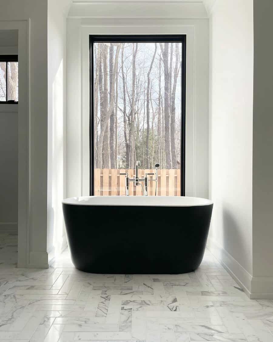 Minimalist bathroom with black tub and forest view