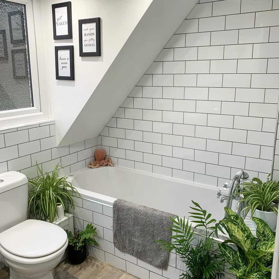 Subway tiled bathroom with alcove tub and slanted ceiling