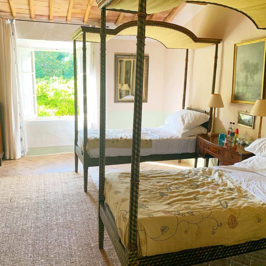 Charming twin canopy beds with woven frames and soft yellow fabric, set in a rustic bedroom with natural light and vintage-inspired decor