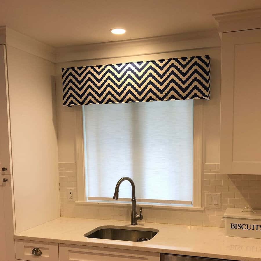 Modern kitchen with a sleek undermount stainless steel sink, high-arch faucet, white subway tile backsplash, and a bold chevron-patterned valance