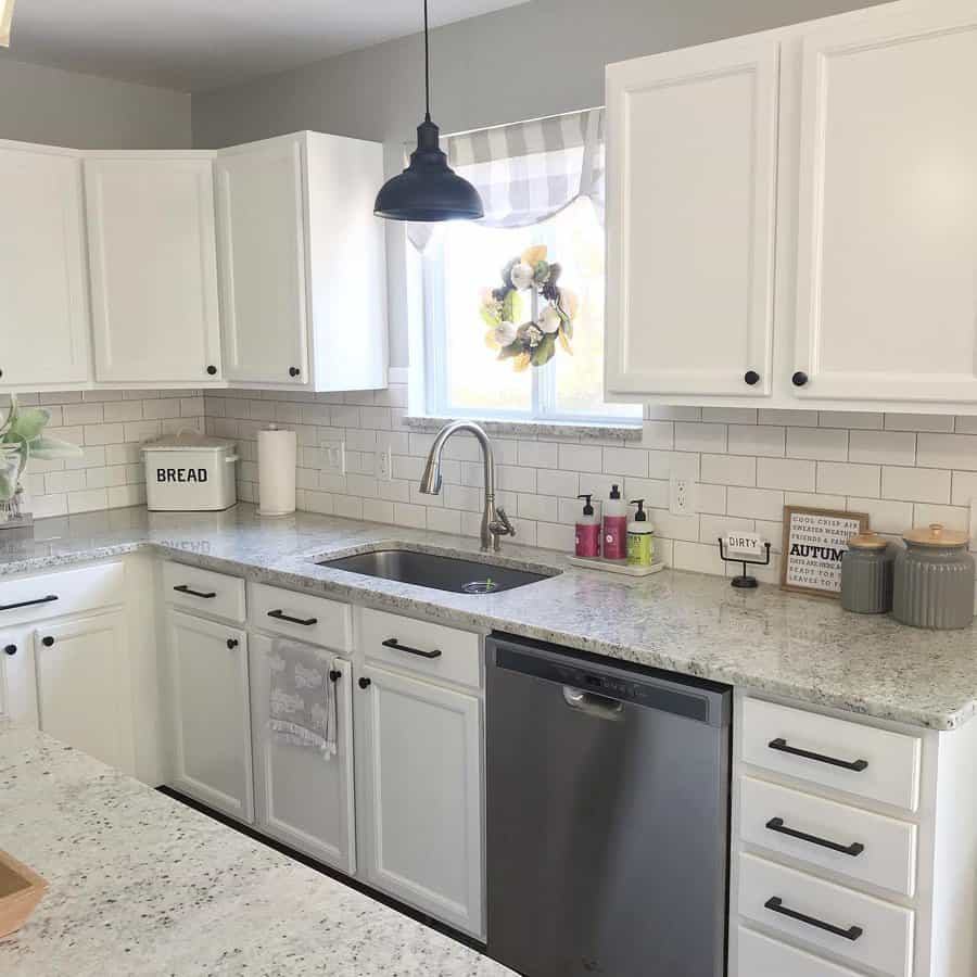 Bright farmhouse kitchen with an undermount sink, brushed nickel faucet, white subway tile backsplash, and granite countertops for a cozy touch