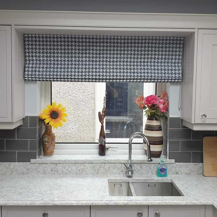 Modern kitchen with a double undermount sink, high-arch faucet, marble countertops, grey subway tile backsplash, and a stylish houndstooth valance