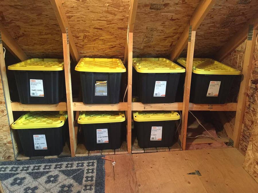 Sturdy wooden attic shelves holding neatly stacked black and yellow storage bins, maximizing space in an unfinished attic.