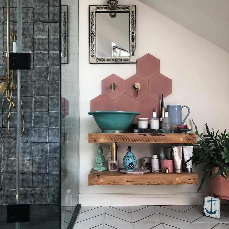 Eclectic bathroom with blush hexagon tile backsplash, teal vessel sink, rustic wood shelves, and vibrant decor for a playful boho vibe.