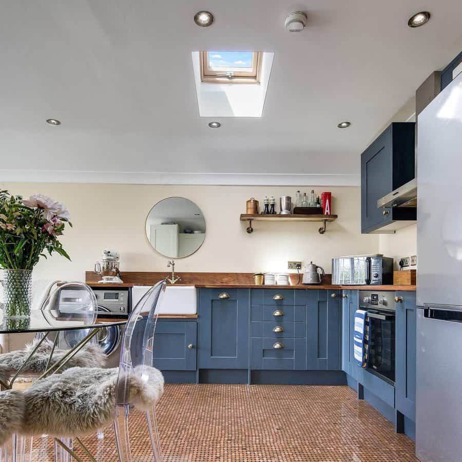 Copper penny tile flooring adds a unique and eye-catching touch to this modern kitchen, complementing deep blue cabinetry and warm wood accents