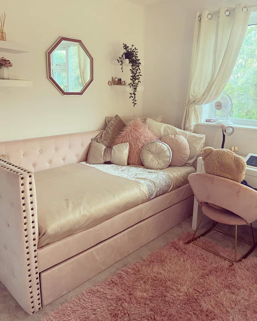 Elegant blush pink upholstered daybed with tufted details, plush pillows, and a soft shag rug, creating a cozy and stylish bedroom retreat