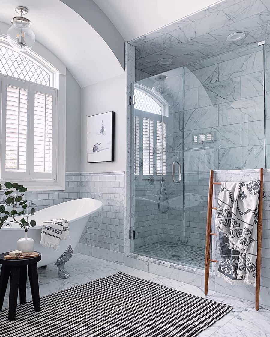 Elegant bathroom with a vaulted ceiling, marble surfaces, and a clawfoot tub, creating a bright and sophisticated spa-like retreat.