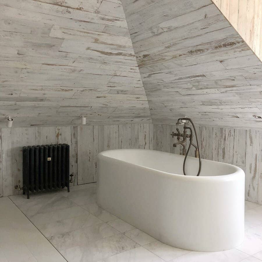 Minimalist bathroom with a rustic vaulted ceiling, weathered wood paneling, and a sleek freestanding tub, creating a serene and spa-like retreat.