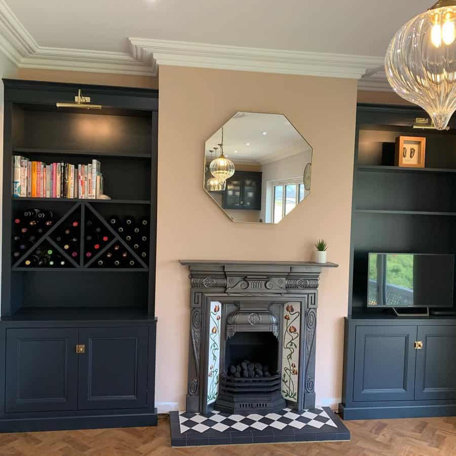 A charming Victorian-style fireplace with intricate tile work, surrounded by dark shelving and a sleek mirror above, creating a cozy and stylish focal point