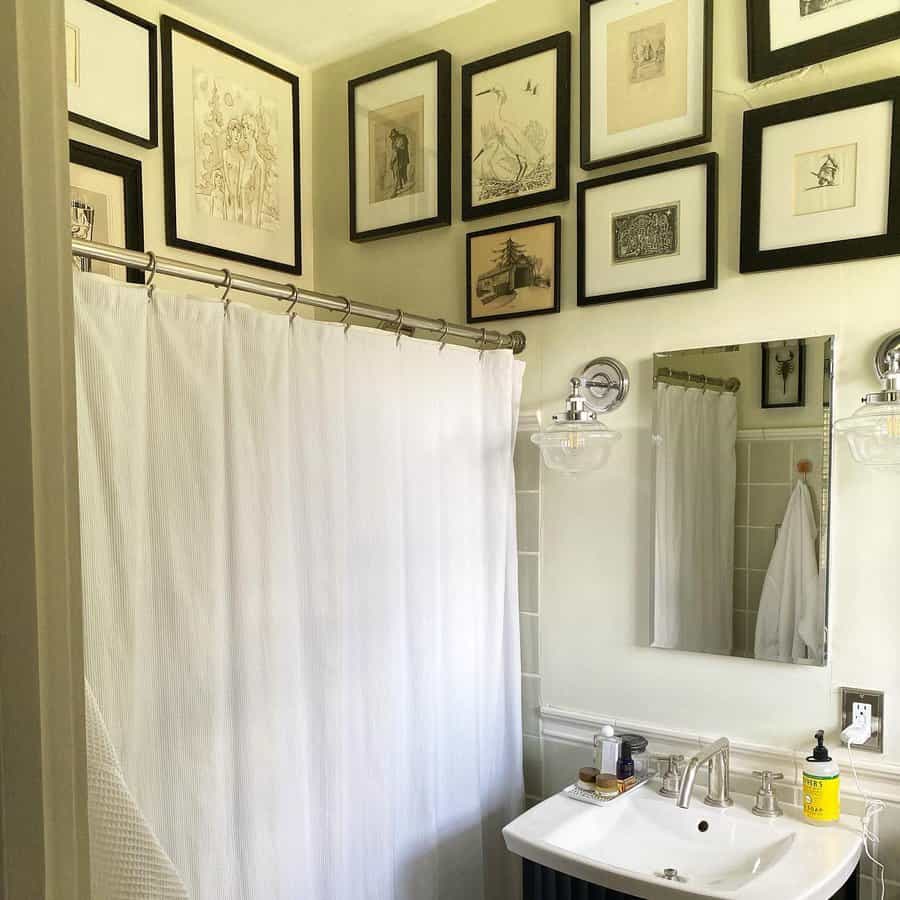 Framed sketches on white bathroom wall 