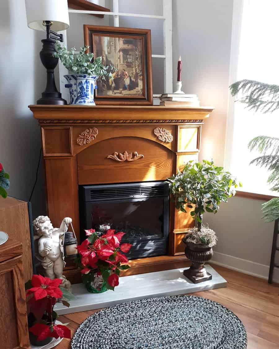 Cozy living room corner with a wooden fireplace, framed art, decorative plants, a ceramic angel, and red poinsettias