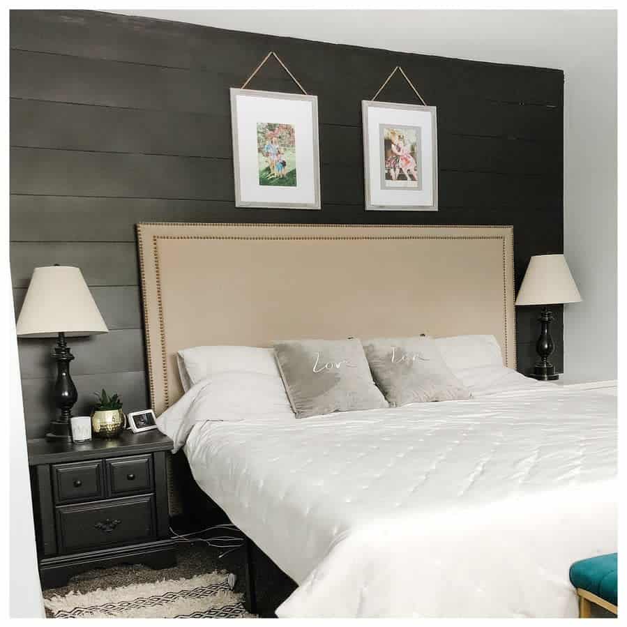 Charming black bedroom with a shiplap accent wall, beige headboard, cozy white bedding, and matching black nightstands and lamps