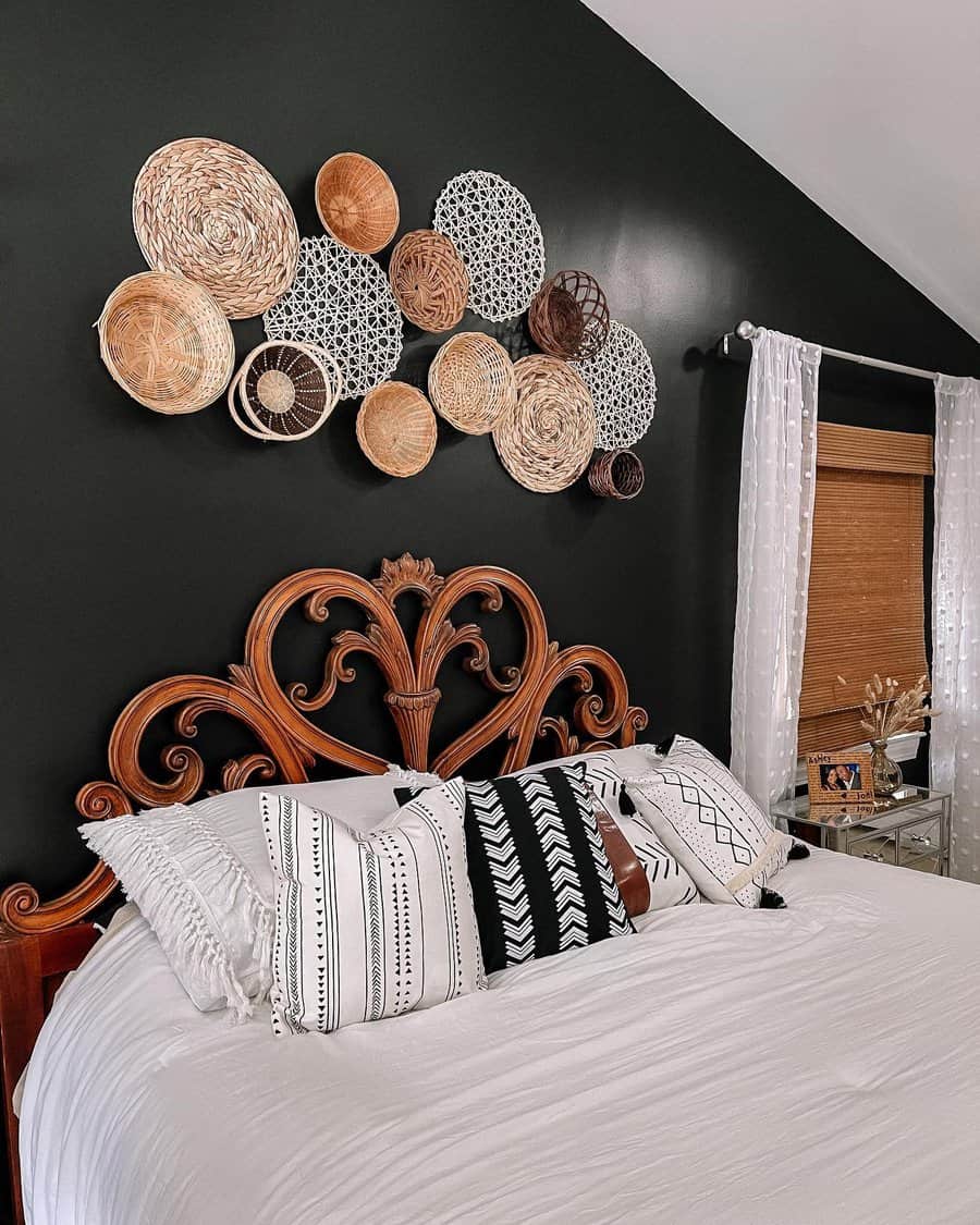 Eclectic black bedroom with a carved wooden headboard, tribal print pillows, and woven basket wall art for a cozy, boho-chic vibe