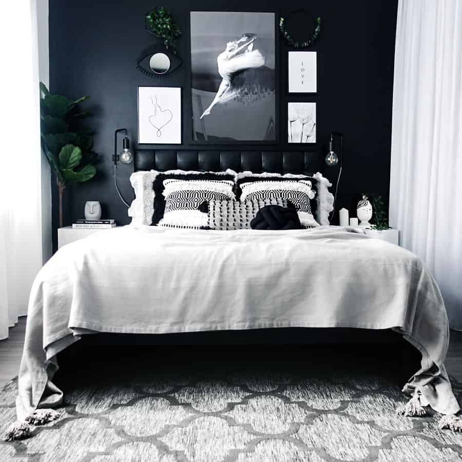 Minimalist bedroom with black walls, monochrome decor, and a cozy bed; abstract art and plants accent the serene space