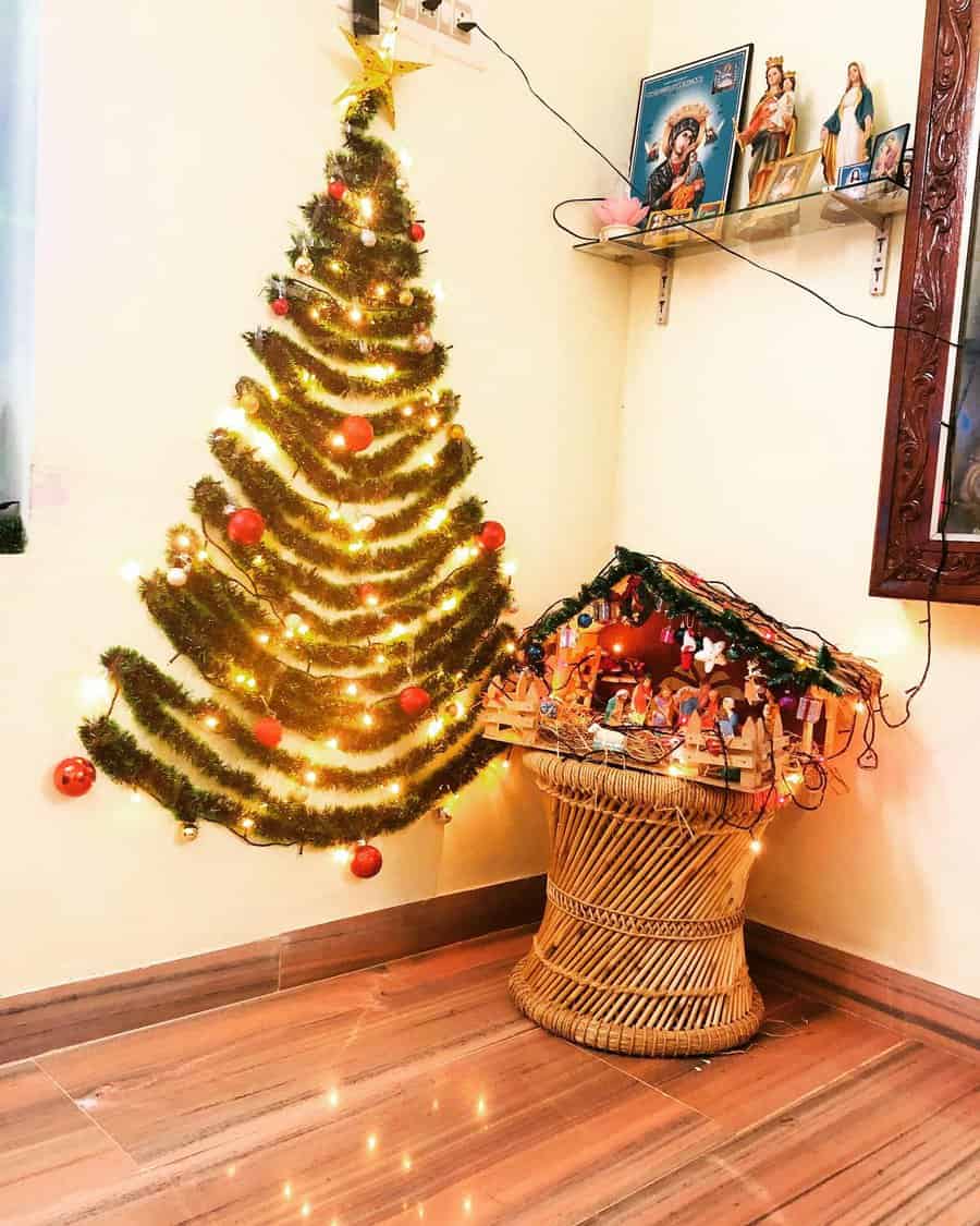 Wall-mounted Christmas tree with lights, red baubles, and a Nativity scene on a basket