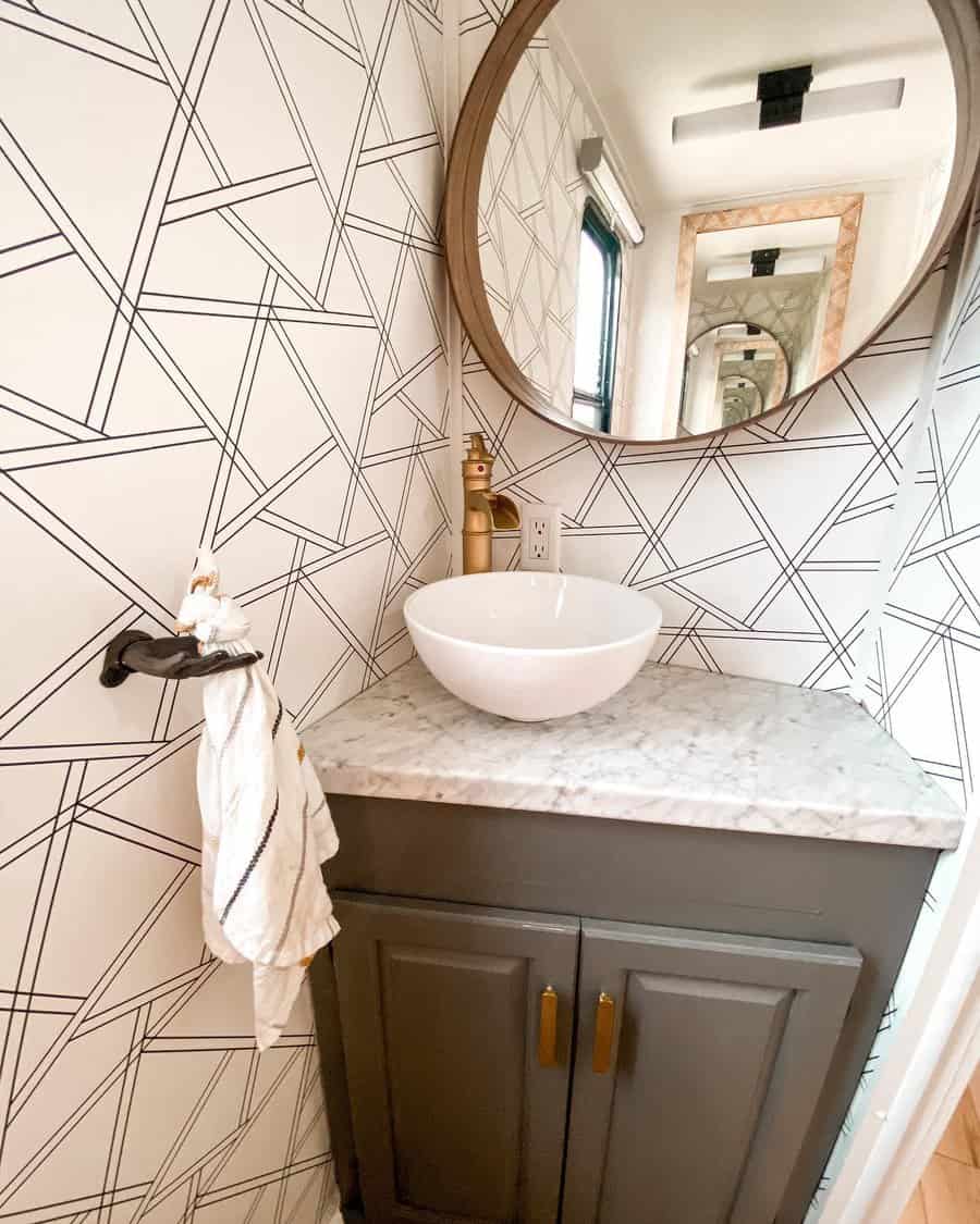 A modern RV bathroom with geometric wall tiles, a round mirror, and a marble countertop, paired with sleek cabinetry and a minimalist design for a stylish, functional look.