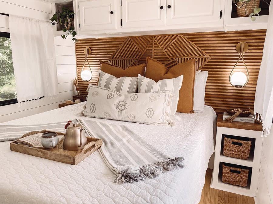 Cozy RV bedroom with slatted wood headboard and neutral decor