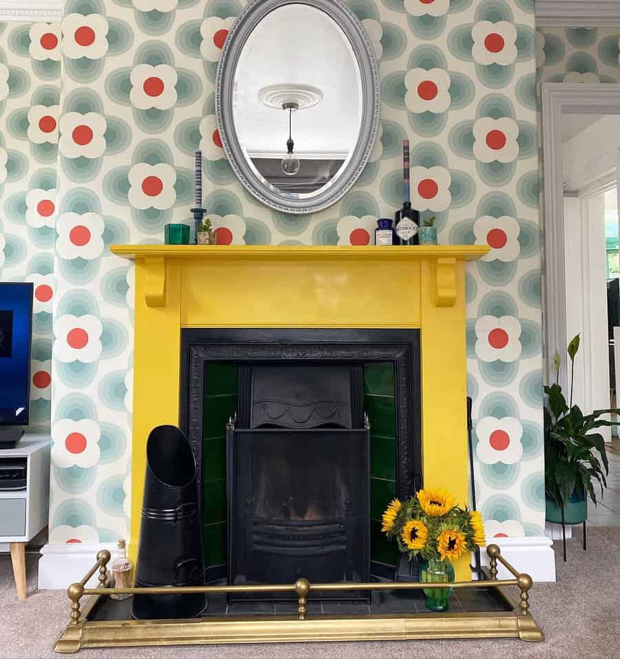 Colorful living room with retro floral wallpaper, yellow fireplace, oval mirror, and sunflowers in a vase on the hearth