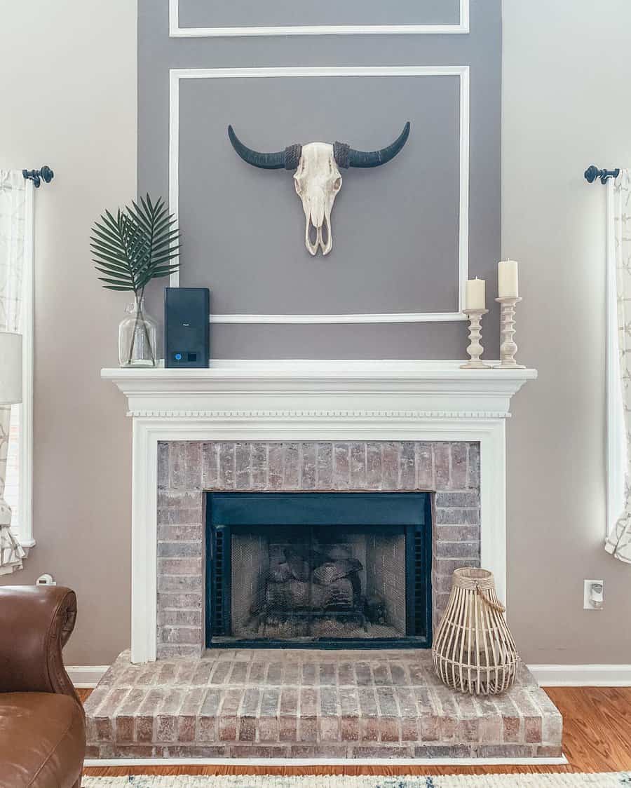 Living room with a brick fireplace, decorative bull skull, candles, and vases on the mantel; neutral tones and modern decor