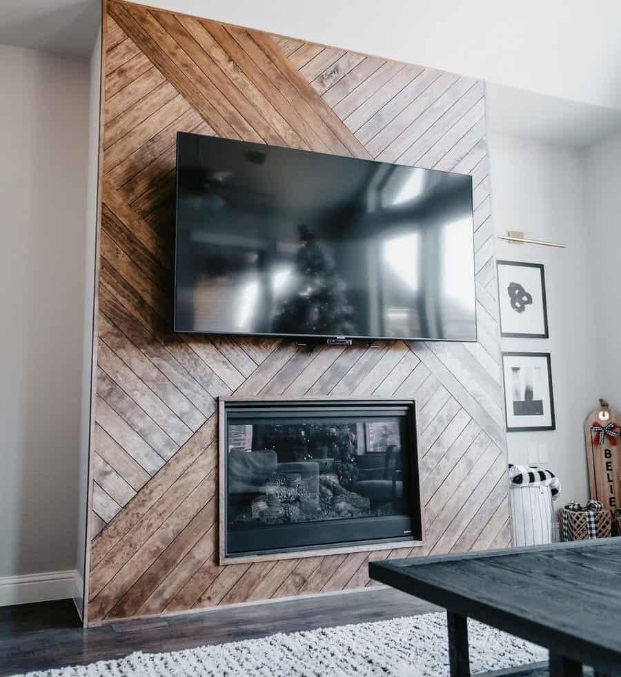 Living room with a wall-mounted TV above a fireplace, framed by diagonal wood paneling