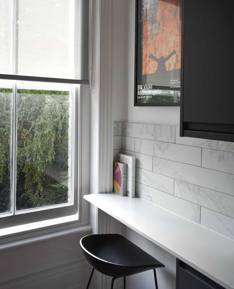 Minimalist window-side work area with sleek chair and poster