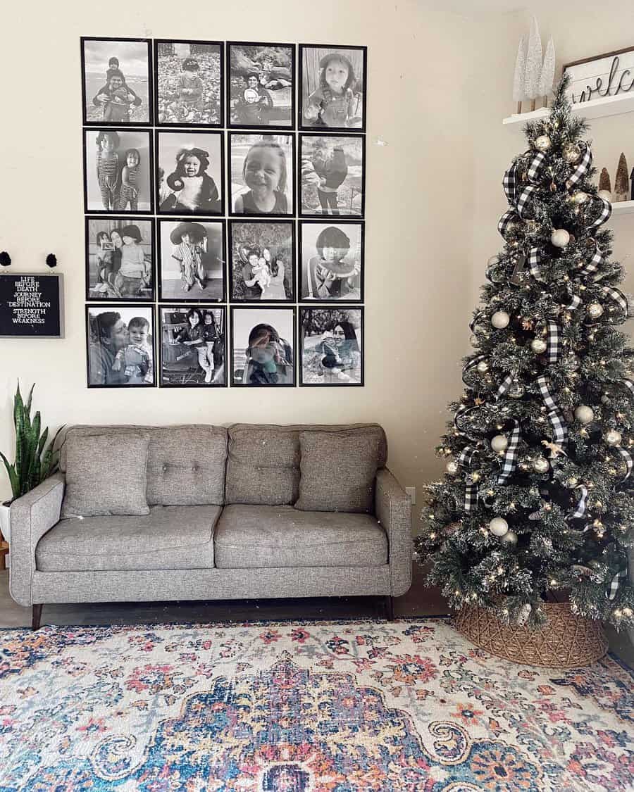 Living room with a gray sofa, collage wall art, decorative Christmas tree, patterned rug, and a small plant