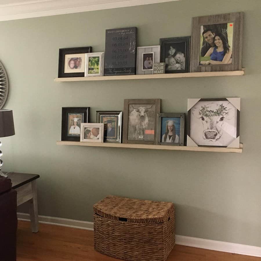 Two wall shelves with various family photos in frames, a small table with a lamp, and a wicker basket below on the wooden floor