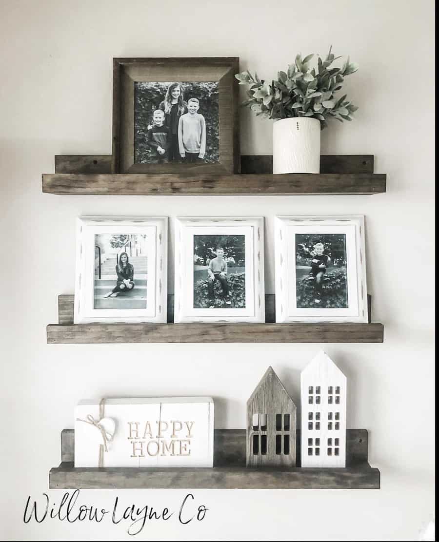 Wall shelves with family photos, a potted plant, and wooden house decor