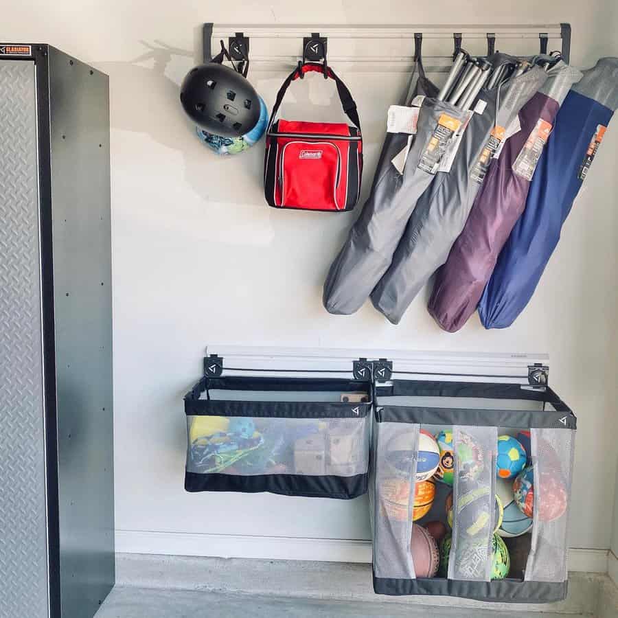 Garage wall storage with hanging helmets, chairs, a cooler, and mesh bins containing balls