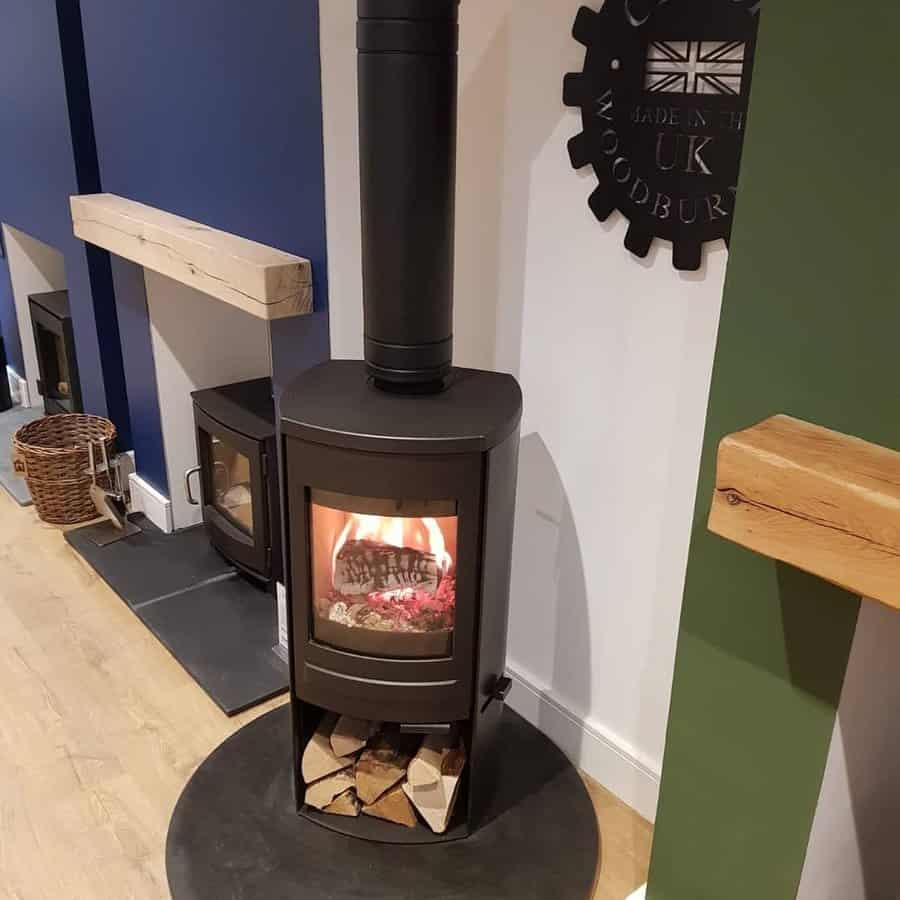 Modern freestanding wood stove with a sleek black design, built-in log storage, and a circular hearth, creating a stylish and cozy focal point.