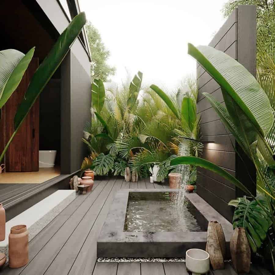 Outdoor patio with a small rectangular pool, surrounded by lush green plants and pottery