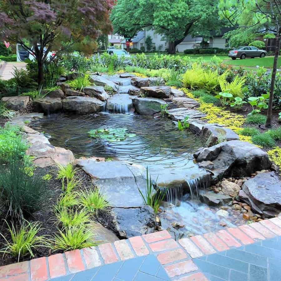 A serene garden pond with cascading waterfalls, surrounded by lush greenery and colorful plants