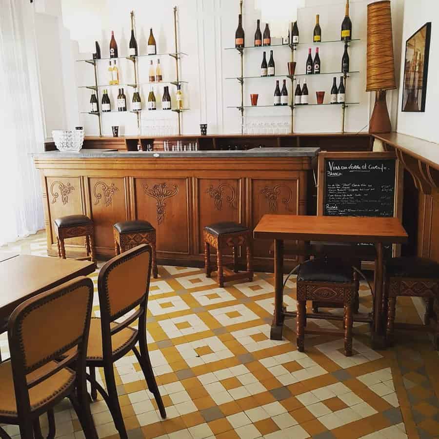 Bar setting with wooden furniture and bottles on the wall