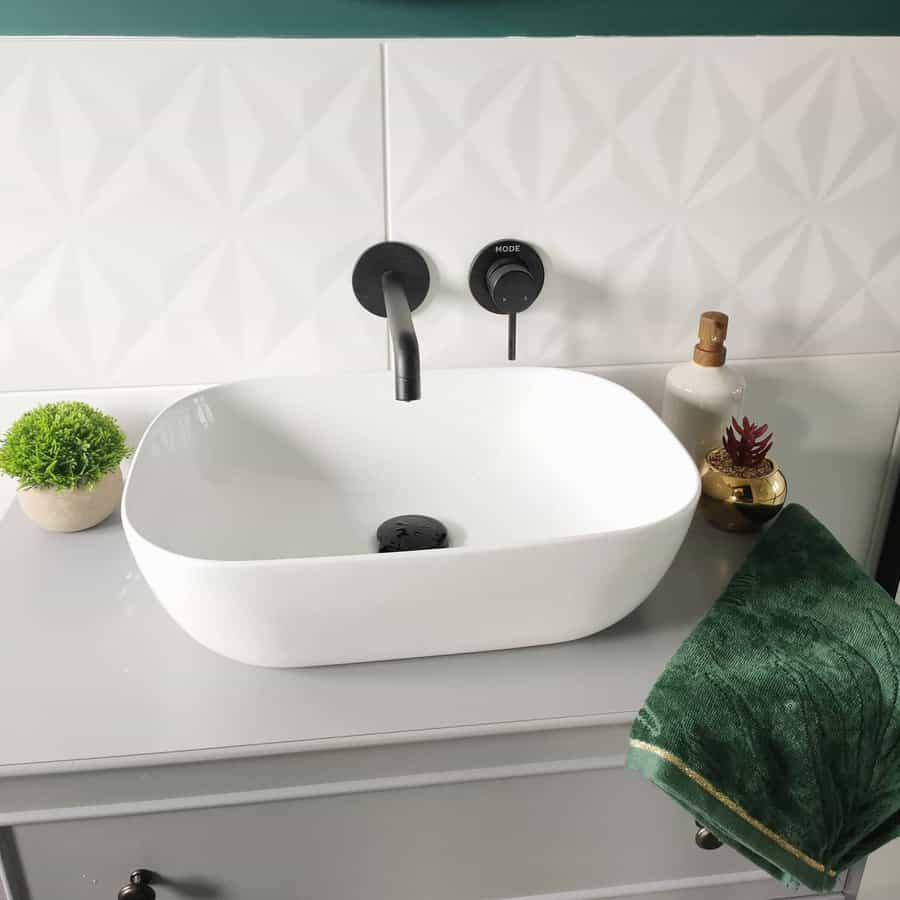 Modern bathroom with subtle geometric white tile backsplash, matte black wall-mounted faucet, and sleek vessel sink for a clean, stylish look.