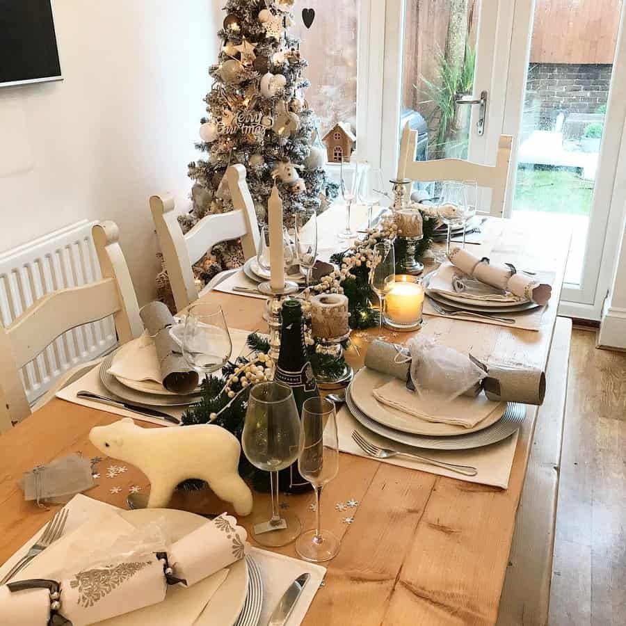 Festive dining table setup with Christmas decorations and a tree in the background