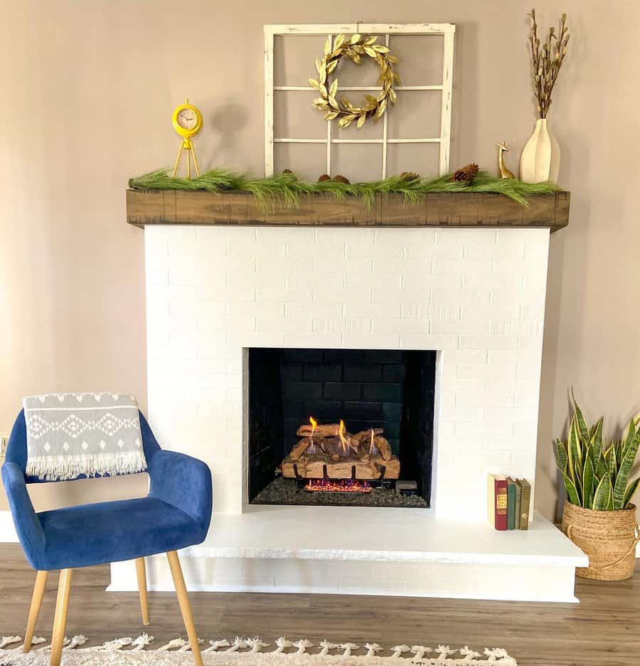 A minimalist white brick fireplace with a wooden mantel, decorated with a wreath, pinecones, and greenery, creating a cozy and welcoming atmosphere