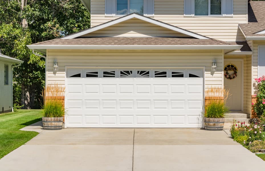 Suburban home with a white paneled garage door and greenery