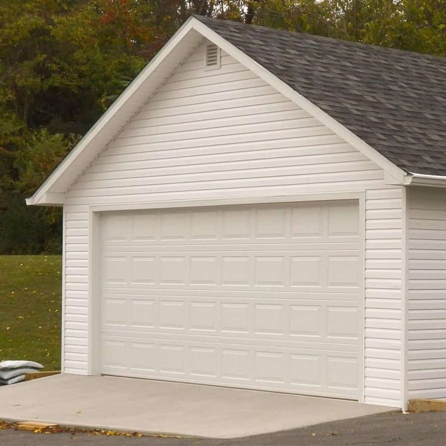 Simple white garage on a siding house with asphalt shingles