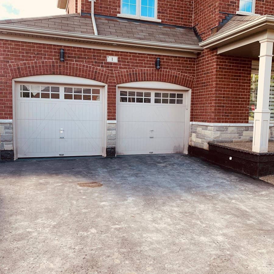 Double white arched garage doors on a brick house