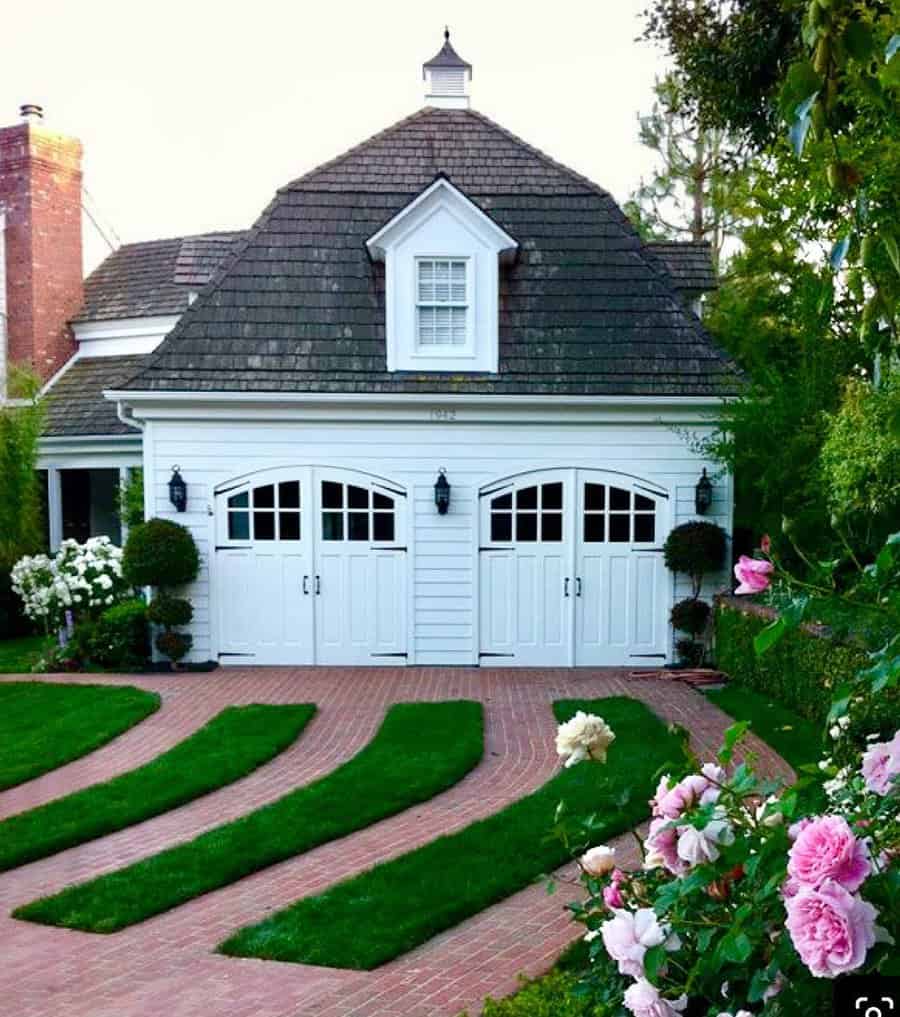 Charming garage with white doors and a landscaped driveway