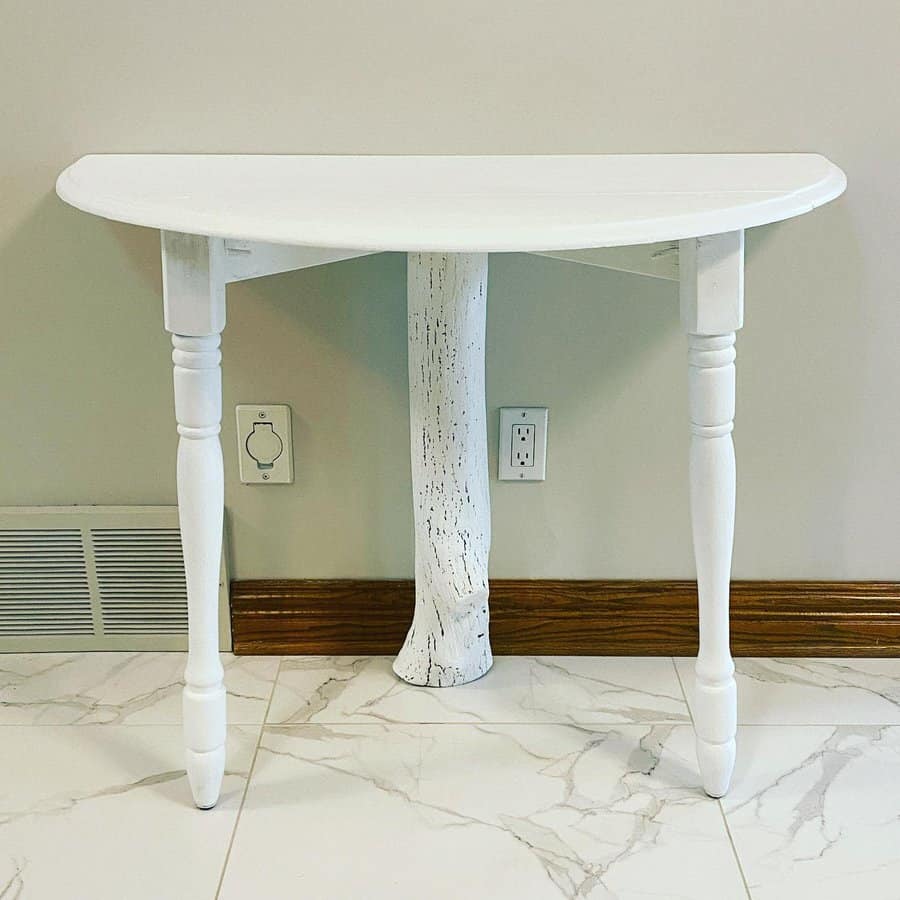 Unique white-painted half-moon table with turned legs and a rustic tree trunk support, blending farmhouse and nature-inspired design.