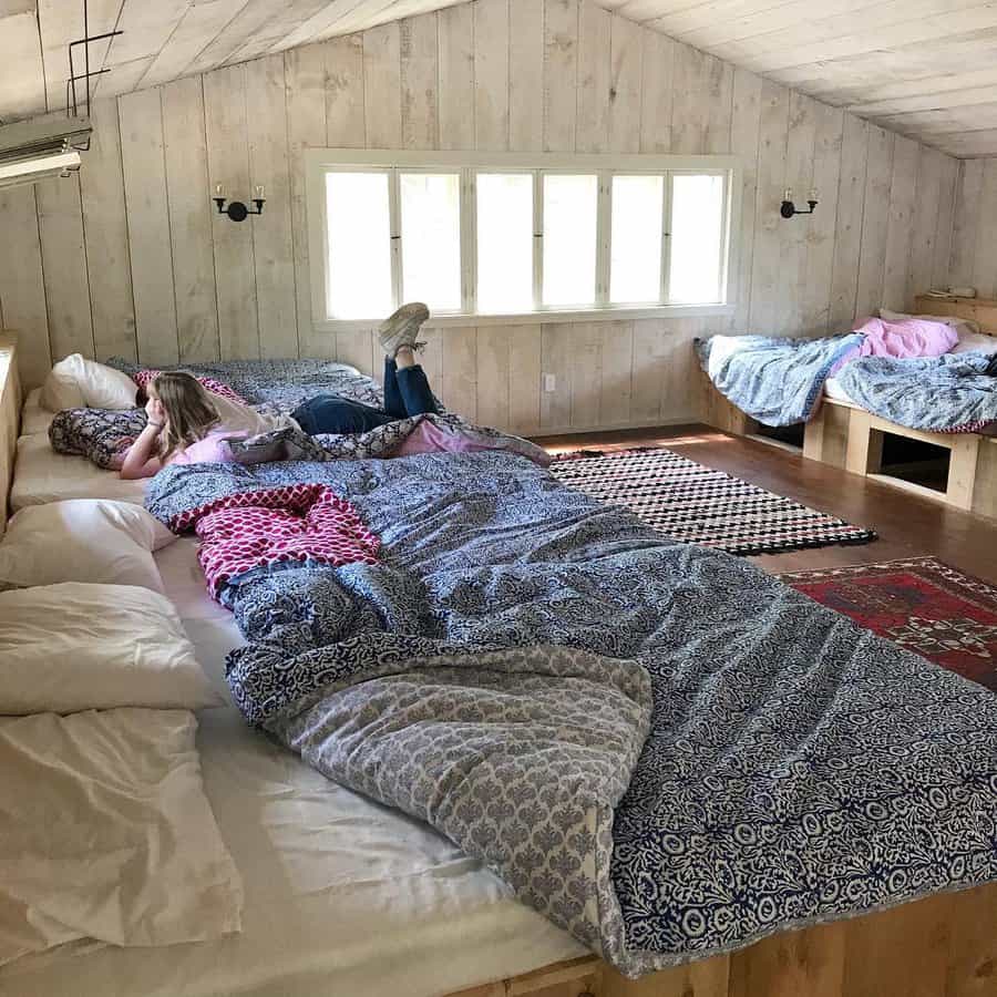 Spacious attic bedroom with whitewashed shiplap walls and multiple beds