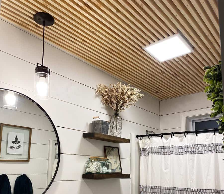 Modern farmhouse bathroom with a slatted wood ceiling, shiplap walls, and black accents, creating a warm and stylish contrast.