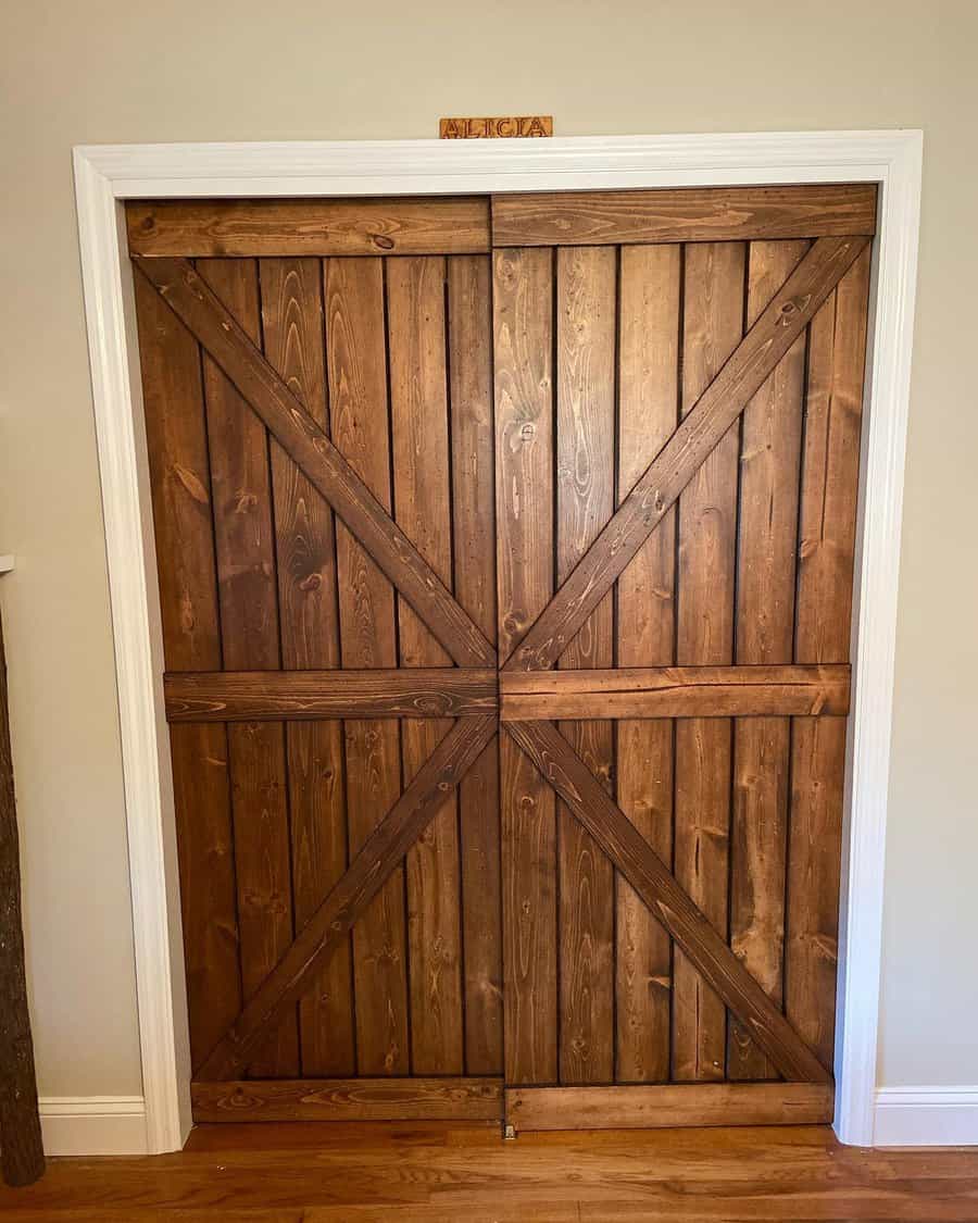 Rustic wooden barn-style closet doors with a classic X-brace design bring a warm, farmhouse touch to this cozy space with hardwood flooring