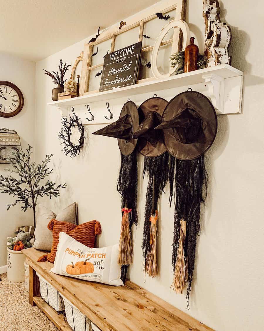 Rustic farmhouse entryway with Halloween decor, a wooden bench, cozy fall pillows, and witch hats hanging on hooks for a festive touch