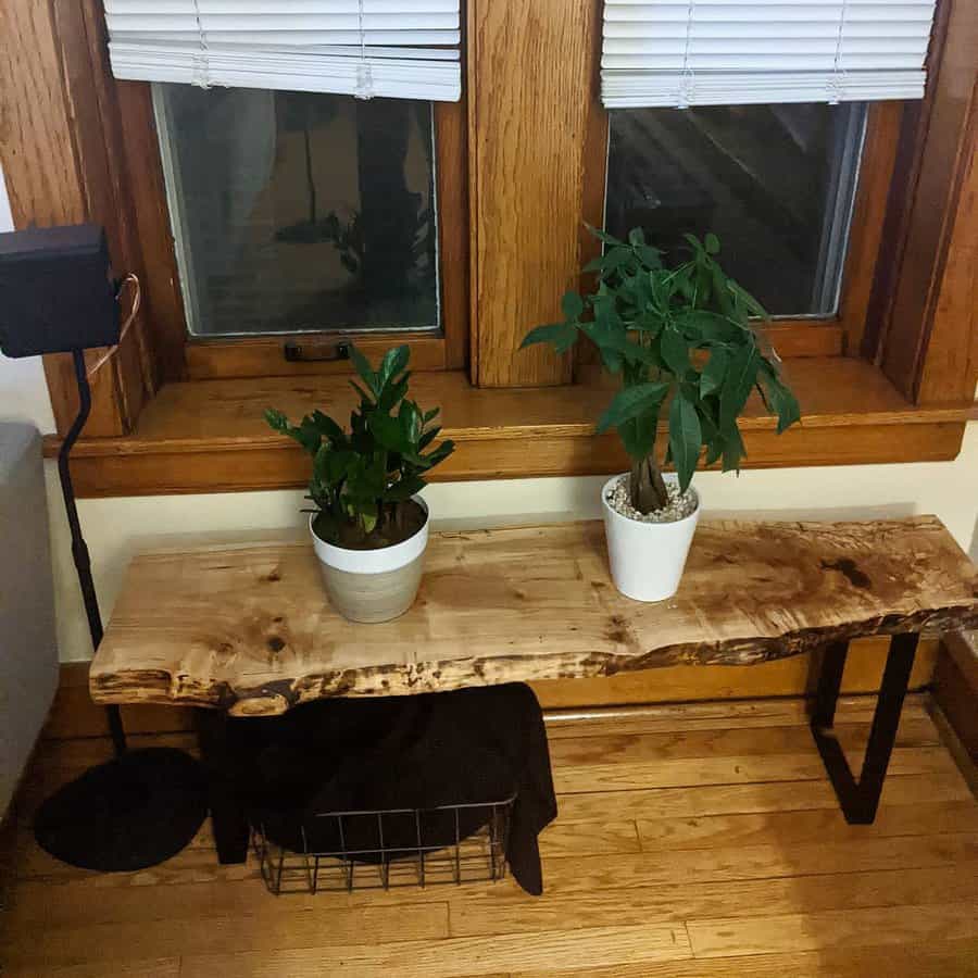 Rustic entryway with a live-edge wood bench, black metal legs, and potted greenery, creating a warm and natural aesthetic