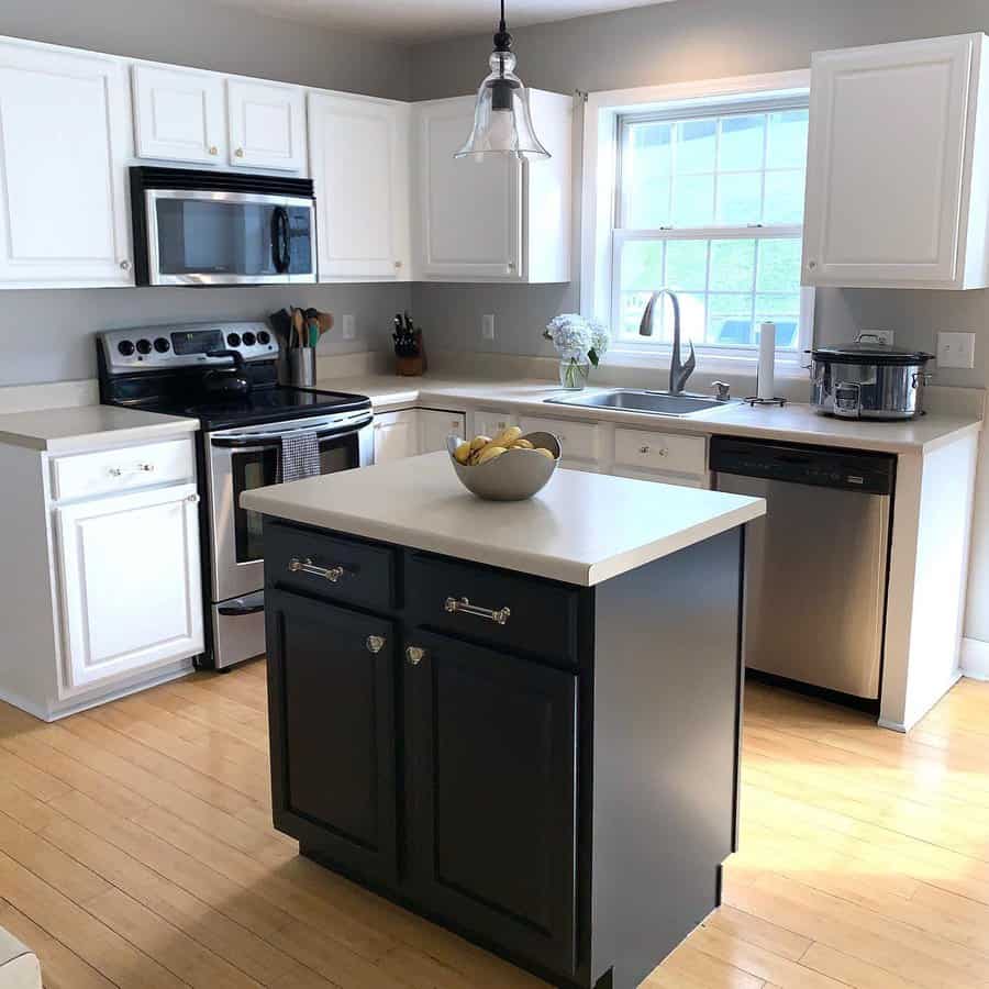 Light hardwood flooring brightens this classic kitchen, complementing white cabinetry and a contrasting dark island for a timeless and inviting look